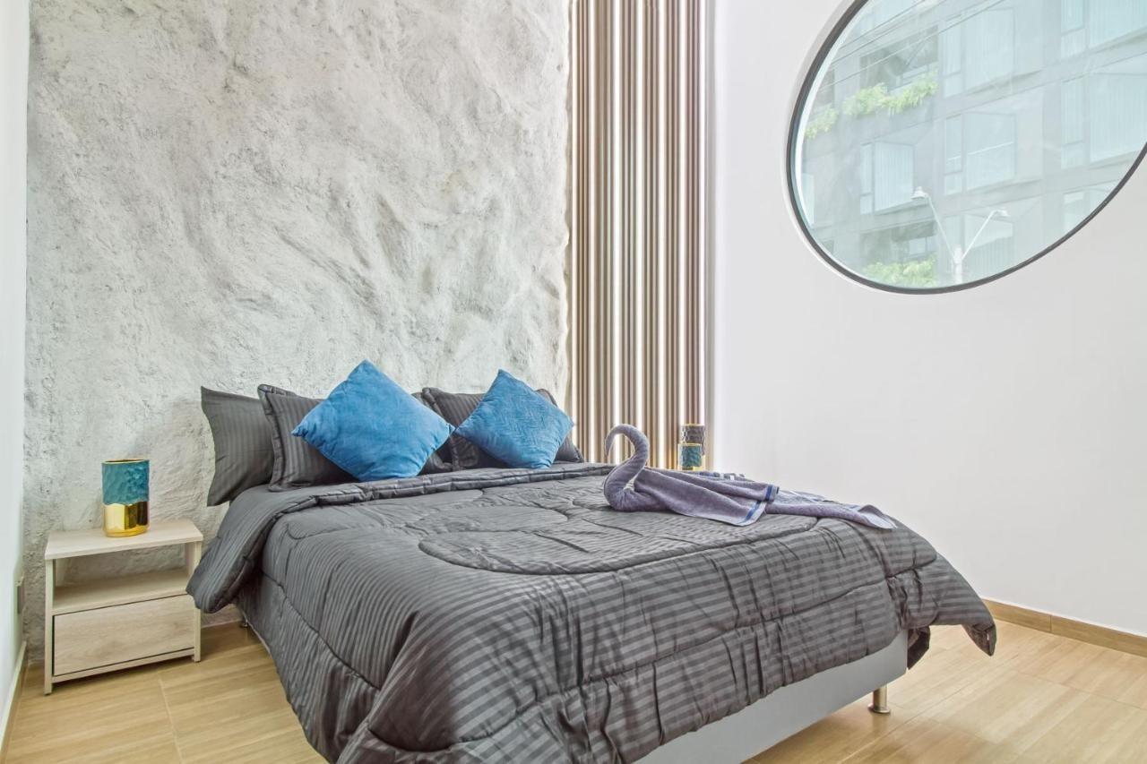 Habitación moderna con cama doble y ventana circular en apartamento de Medellín cerca Parque Lleras