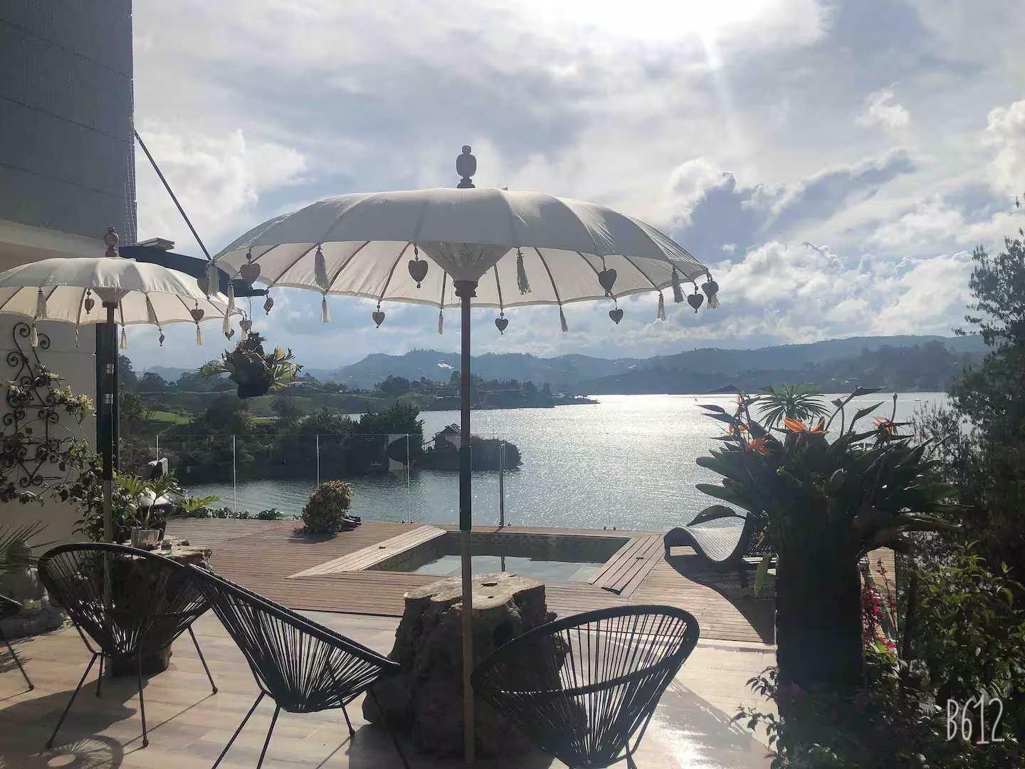 Terraza privada con sombrillas balinesas y vista panorámica al lago en villa de lujo Guatapé Peñol