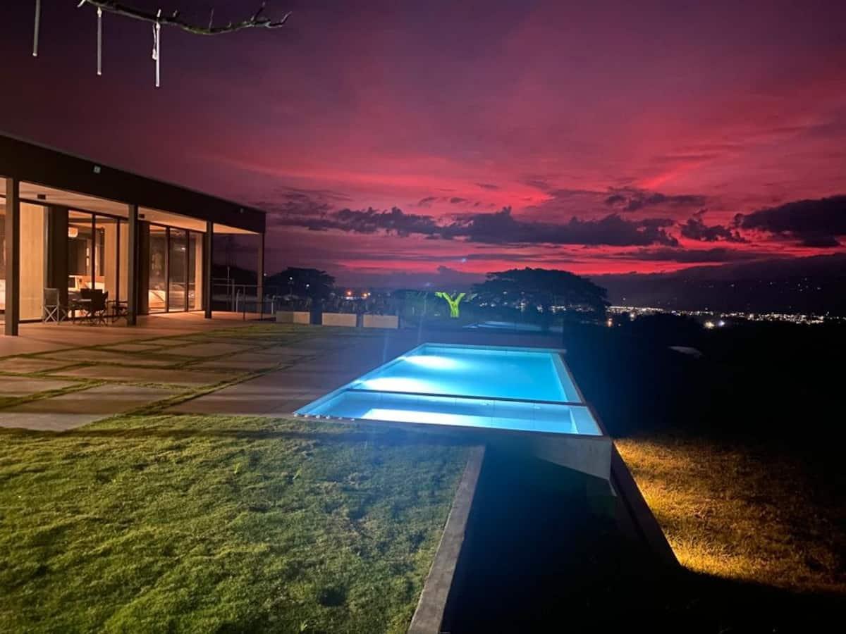 Casa moderna con piscina iluminada al atardecer en Montenegro, Quindío, con vista panorámica montañosa