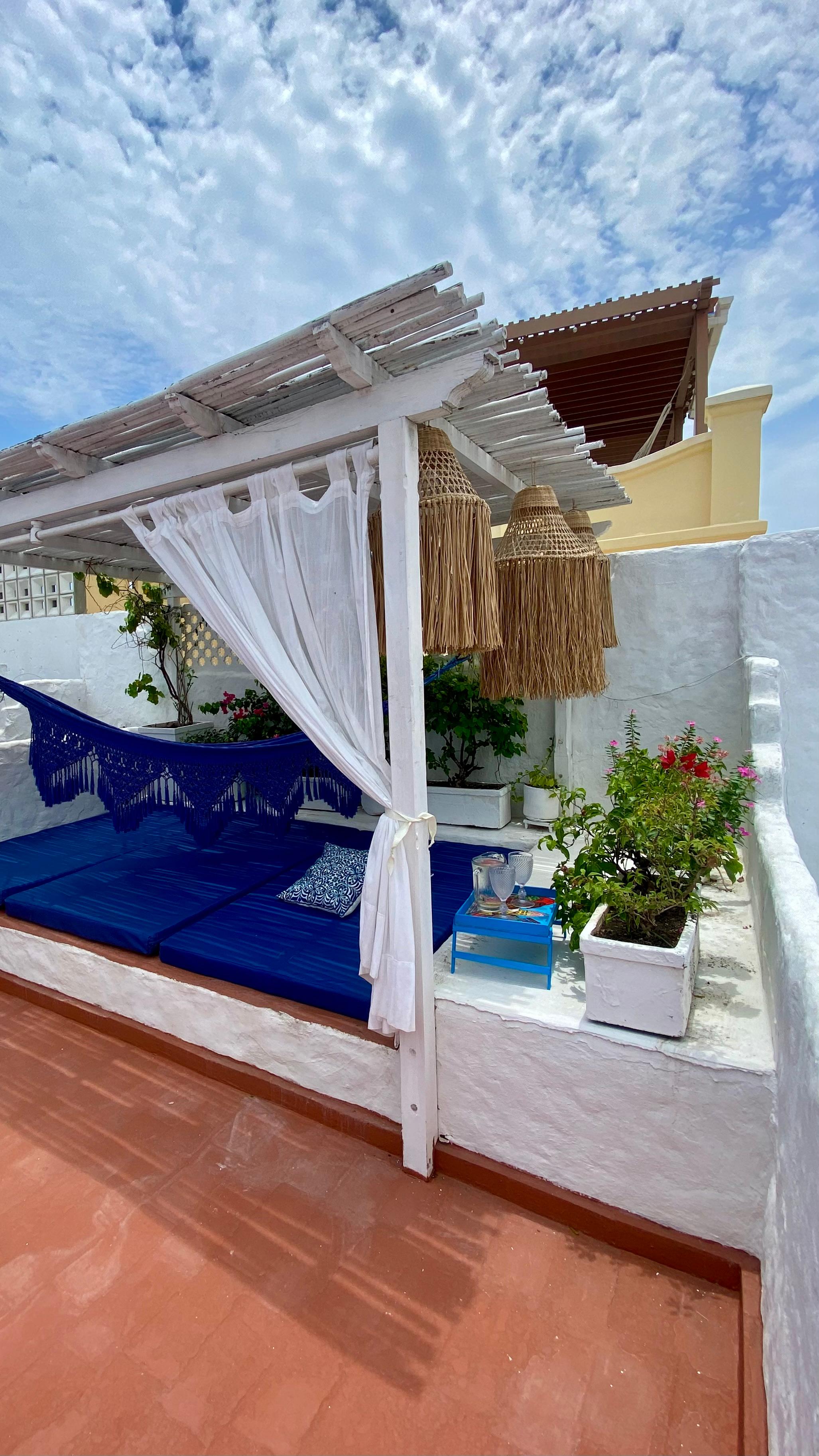 Terraza privada con pérgola, hamaca azul y plantas en casa de Cartagena de Indias