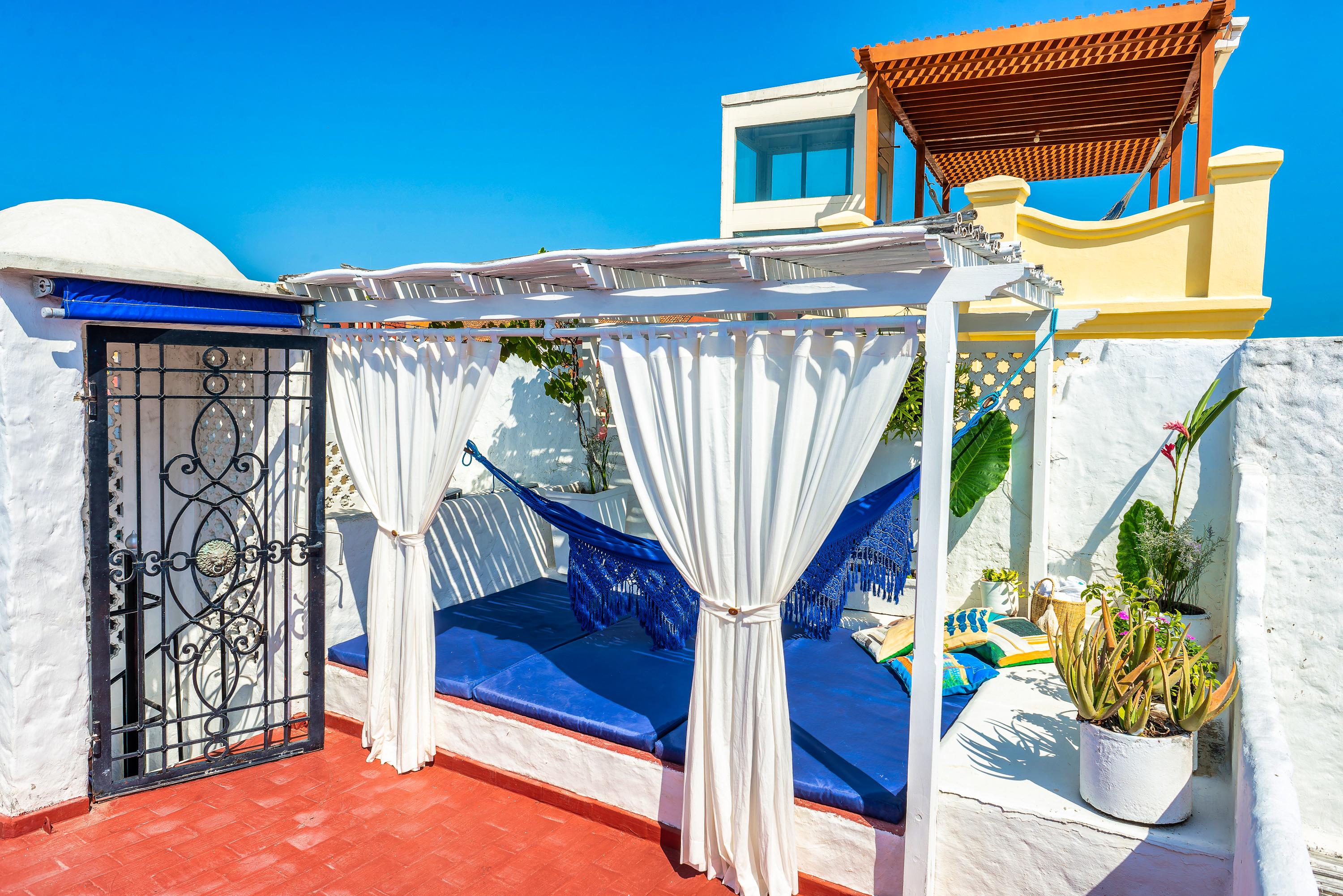 Terraza privada con zona de descanso y cortinas blancas en casa de Cartagena de Indias
