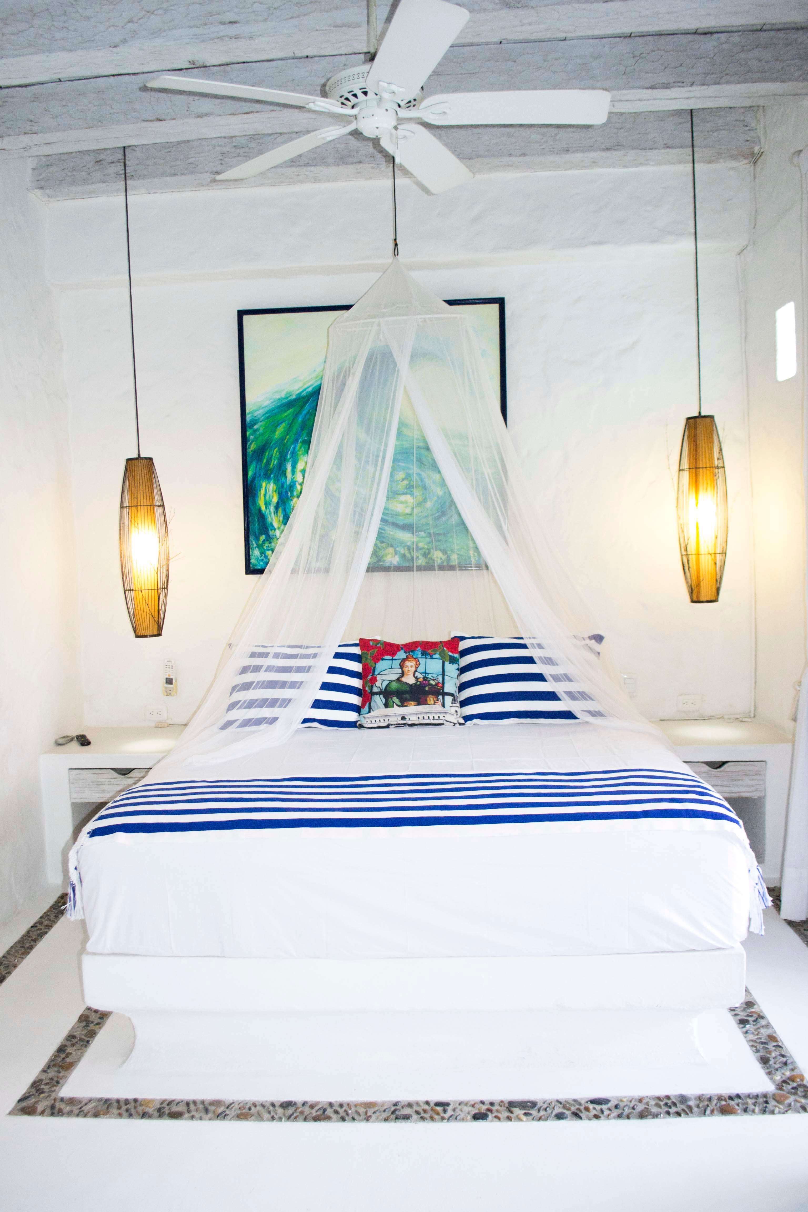 Habitación principal con cama matrimonial, ventilador de techo y lámparas colgantes en casa privada Cartagena de Indias