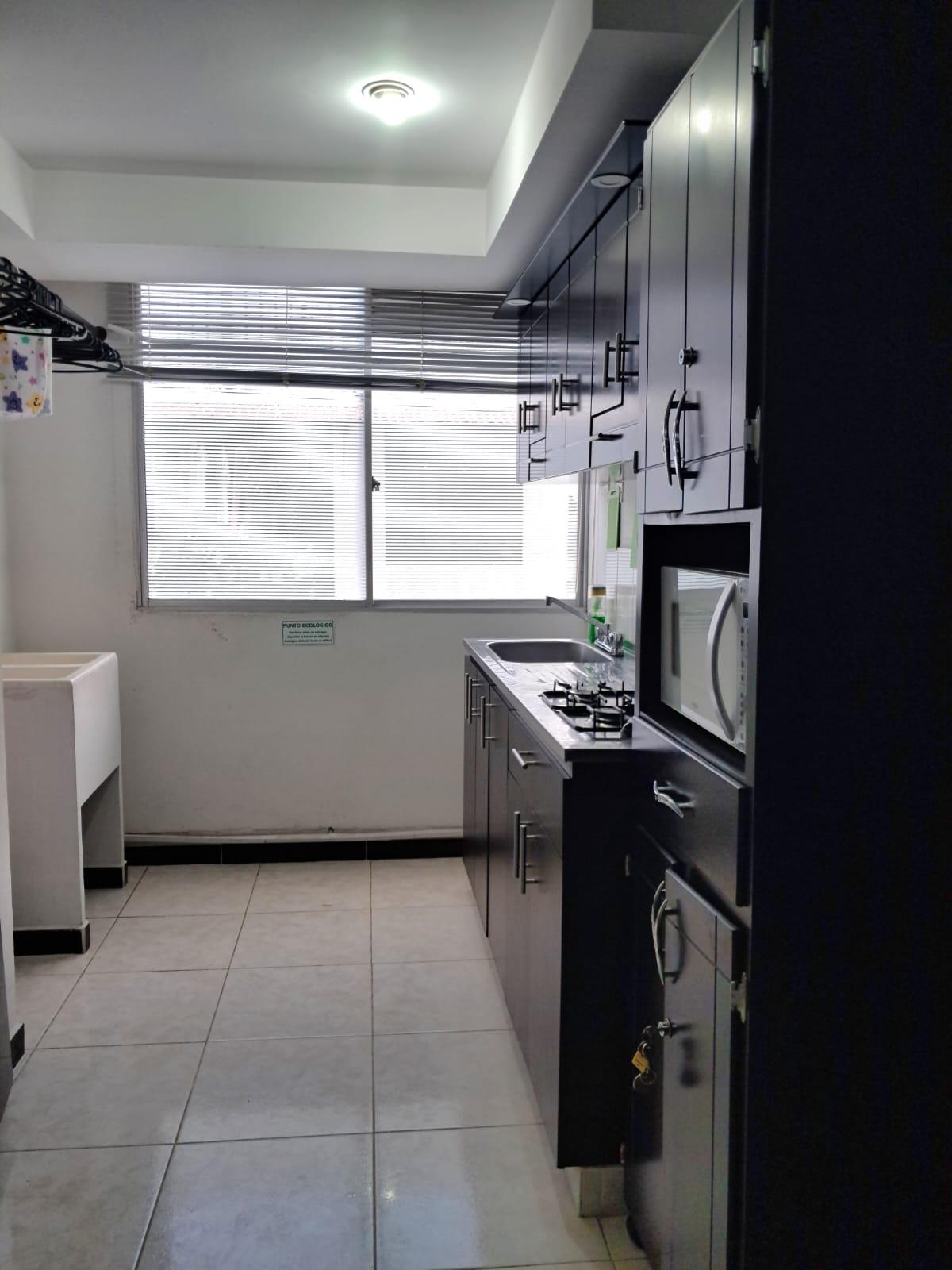 Cocina moderna completamente equipada con gabinetes grises y electrodomésticos en apartamento Montenegro