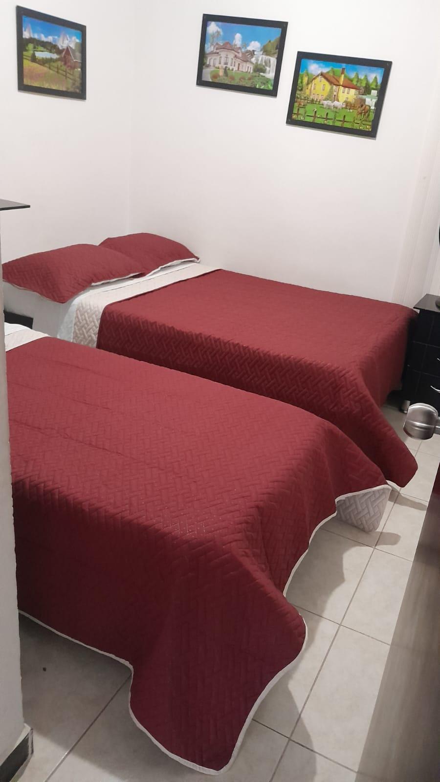 Habitación con dos camas individuales y colchas rojas en apartamento Rincón del Café Montenegro